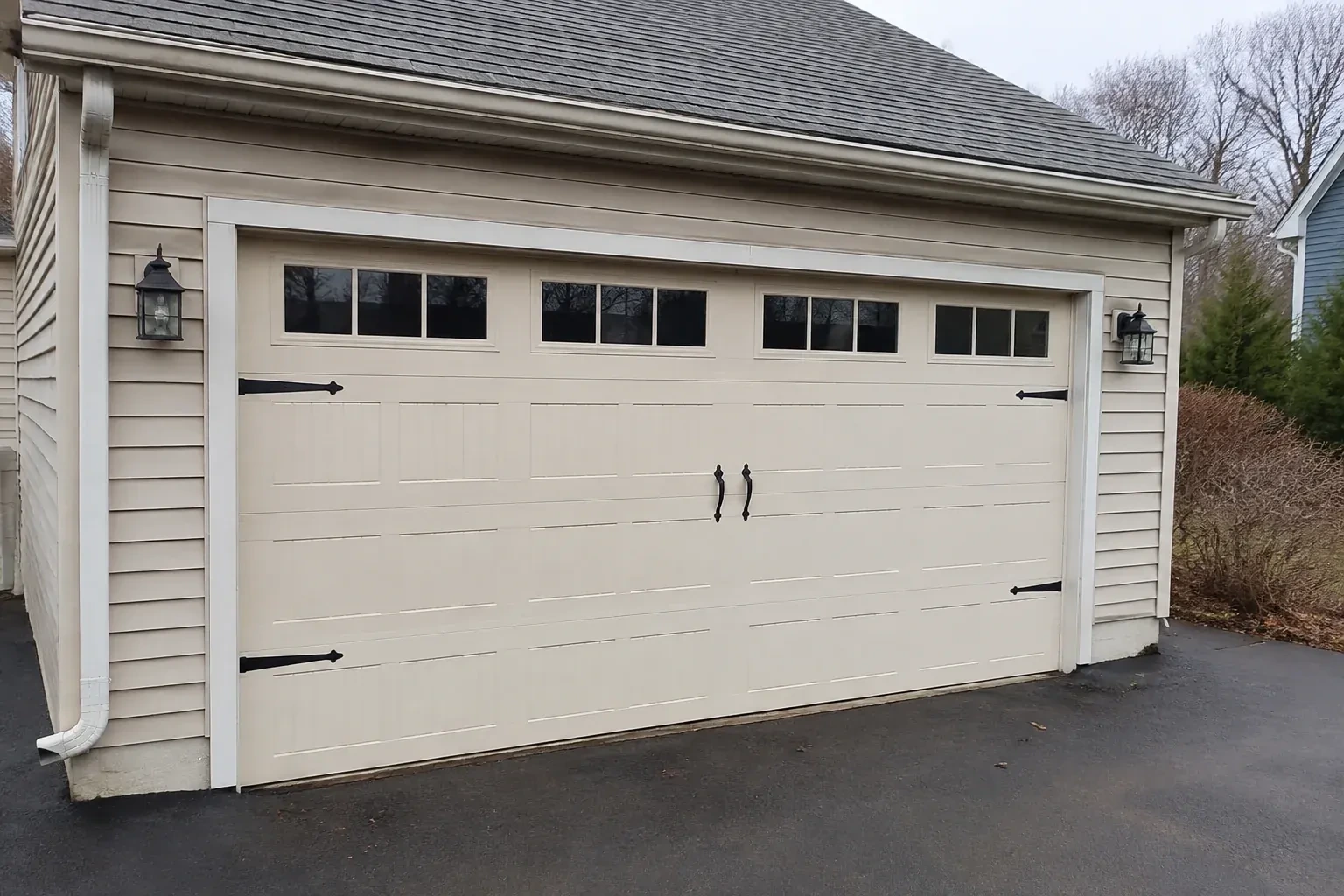 Cream carriage-house-style garage door with dark decorative hardware. — Carriage-House Garage Door Installation, Whitby