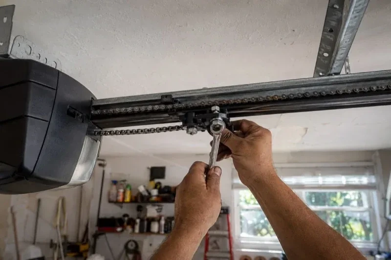 Hands holding a wrench against an opener trolley beneath a chain rail — Chain-Drive Opener Repair, Whitby
